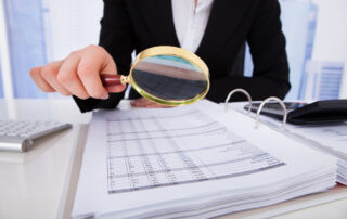 Paying too much for an audit, business person looking at file with magnifying glass