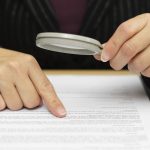 buying a business, looking at contract with magnifying glass