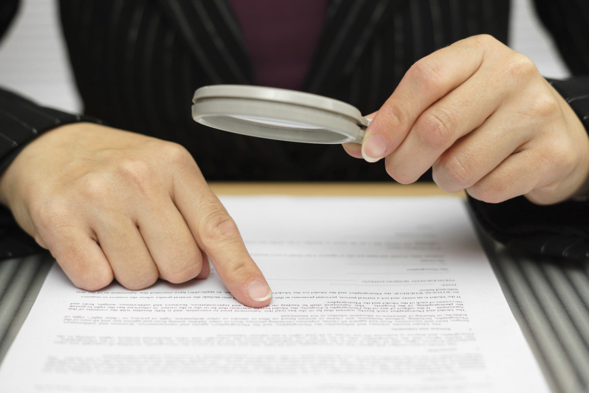 buying a business, looking at contract with magnifying glass